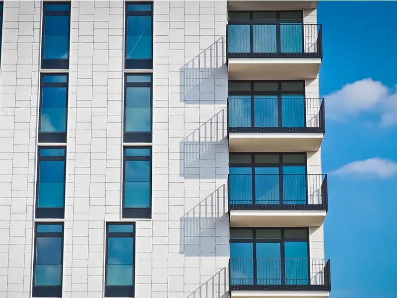 Modern apartment building with balconies beneath a blue sky.