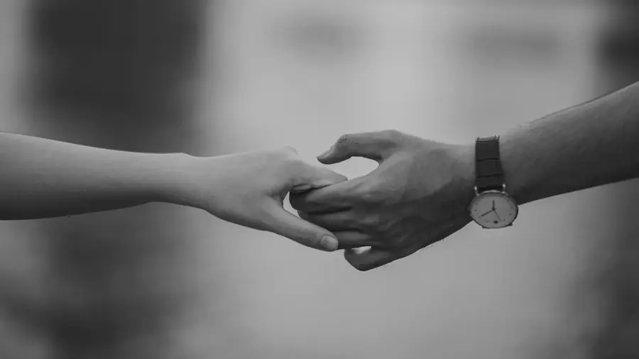 lack-and-white photograph of two people holding hands.