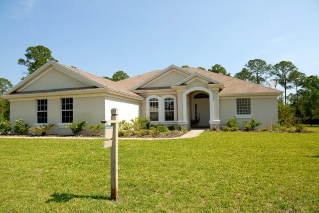 Single-story house with a front lawn and a real estate sign.