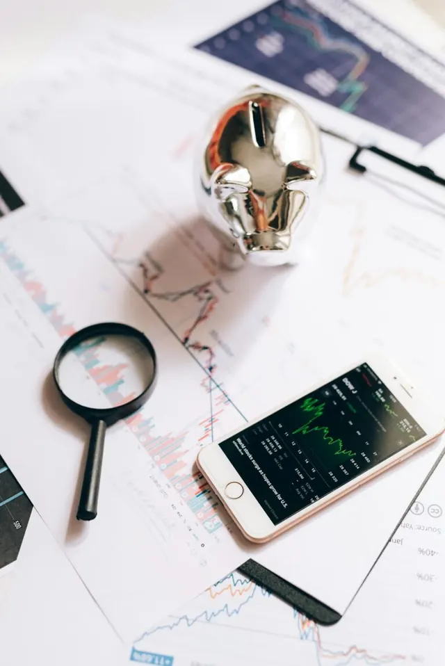 Financial charts, a calculator, and a magnifying glass on a desk.