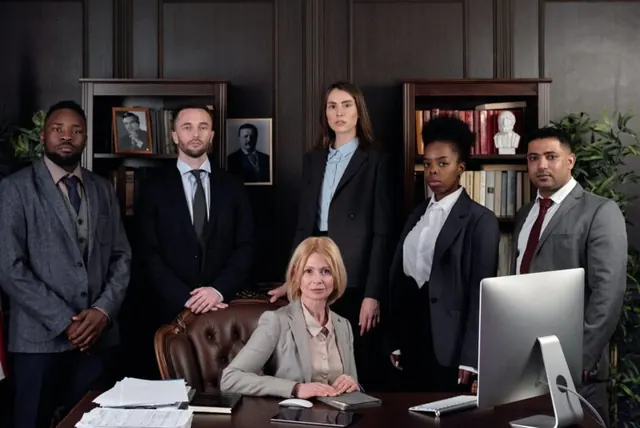 Six business professionals gathered around a desk in an office.