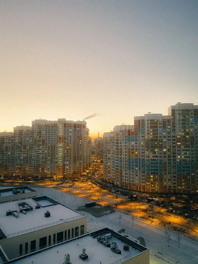 Multistory apartment buildings overlooking an illuminated street at dusk.